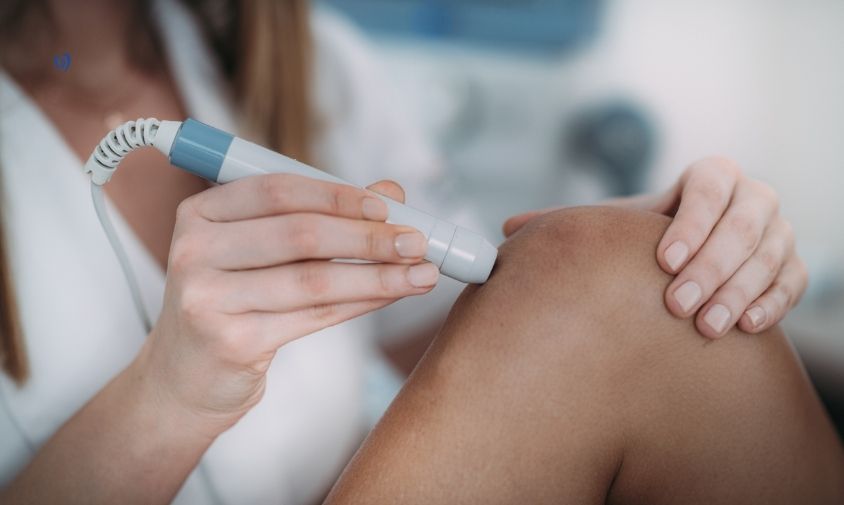 A Class IV laser handpiece being applied over a patient's knee